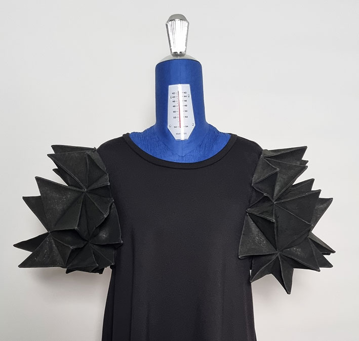 Dress with polyhedron sleeves on a dressform.