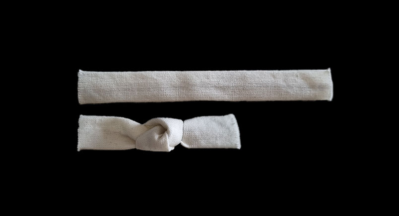Two strips of fabric: one straight and one tied into a knot, to discover how much extra length the knot needs.